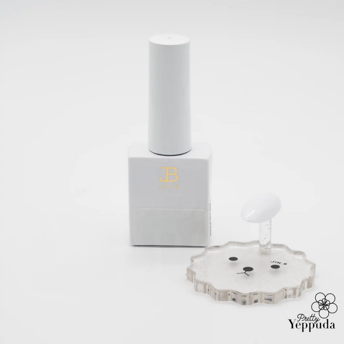 Elegant white bottle of JIN.B IVY Color Gel White nail polish, featuring minimalist design with gold lettering. Accompanied by a transparent flower-shaped palette and applicator brush, showcasing the product's professional quality and attention to detail for precise nail art application.