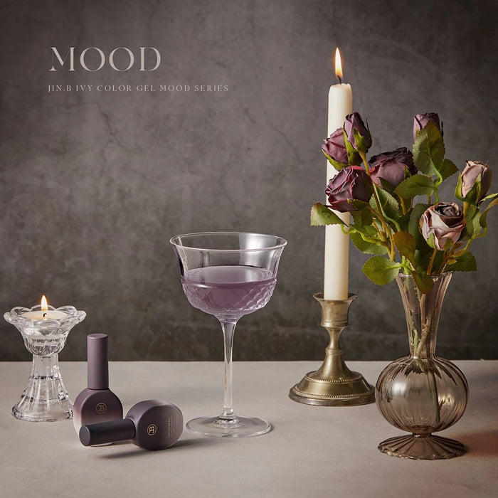 A collection of vintage-inspired, beautifully styled syrup gels from the Jin.B Mood Collection, featuring a delicate floral arrangement, a candle, and a glass of vibrant, jewel-toned liquid, all set against a moody, sophisticated background.