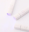 The image shows the MOSTIVE PIN LAMP - SPOT LIGHT, a versatile and hands-free lighting device. The lamp features a stand that can hold a mobile phone, business cards, and art tip cards, making it a second-generation pin lamp. The product offers advantages such as a hands-free stand base, a convex lens for focused curing, and an adjustable pin lamp head angle. This product is designed for easy and convenient use, with a one-minute automatic shut-o