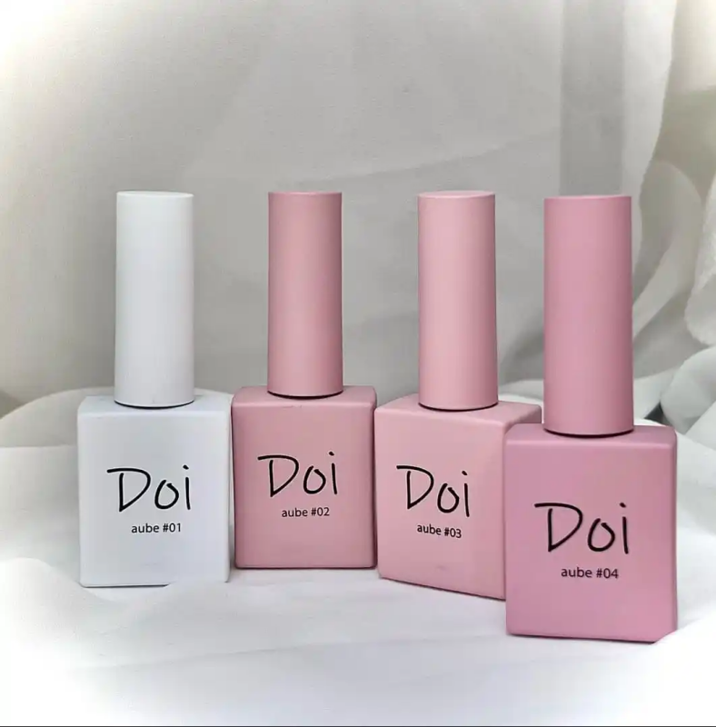Elaborative Alt Text: A collection of four nail polish bottles in pastel colors, including shades of white, pink, and light purple. The products are from the Korean nail brand "Nailbayo" and are part of the "Doi Aube" collection, as indicated by the product names printed on the bottles. The packaging features a clean, minimalist design with a focus on the brand identity and product information.