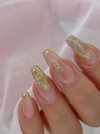 Elegant manicure showcasing Nailbayo DOI Thick Gel in gold and glitter designs on long, coffin-shaped nails. Korean nail art featuring textured gold accents and delicate glitter details, displayed against a soft pink fabric background.