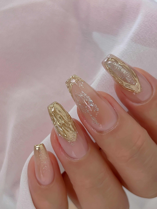 Elegant manicure showcasing Nailbayo DOI Thick Gel in gold and glitter designs on long, coffin-shaped nails. Korean nail art featuring textured gold accents and delicate glitter details, displayed against a soft pink fabric background.