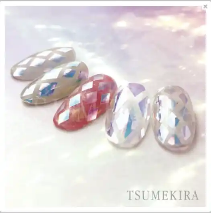 Iridescent diamond-shaped film stickers in vibrant hues, showcasing the Tsumekira brand's Aurora Film Seal Diamond Cut product. The stickers are depicted against a soft, pastel-tinted background, highlighting their prismatic, multi-colored reflections and alluring aesthetic appeal for decorative nail art, accents, and crafting applications.