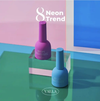 Eight vibrant neon nail polish bottles from the VALLA Neon Trend collection, featuring a bold purple and a striking blue color, displayed on a minimalist geometric backdrop in coordinating shades.